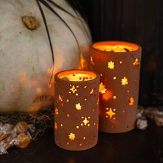 three lit candles sitting on top of a table next to a pumpkin and other decorations