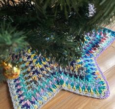 a crocheted star ornament hanging from a christmas tree with pine needles