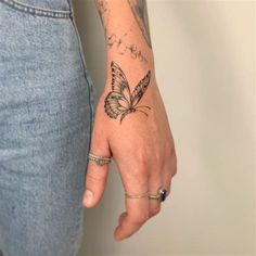 a woman's hand with a butterfly tattoo on her left wrist and the other arm