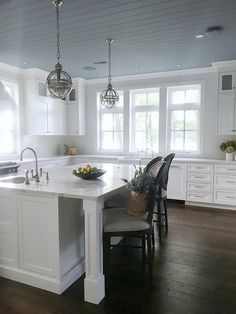 a kitchen with white cabinets and an island in the middle, surrounded by wooden floors