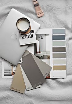 a laptop computer sitting on top of a bed next to color swatches and paint samples