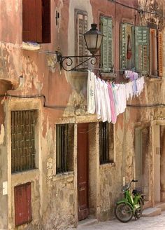 clothes hanging out to dry on a line in front of an old building with windows and shutters