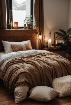 a bed with blankets and pillows in a bedroom next to a window filled with candles