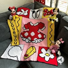 a crocheted blanket with mickey and minnie mouses on it sitting on a couch