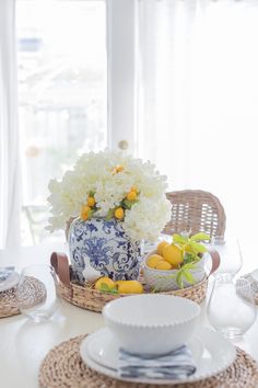 a white table topped with blue and white plates and vases filled with yellow and white flowers