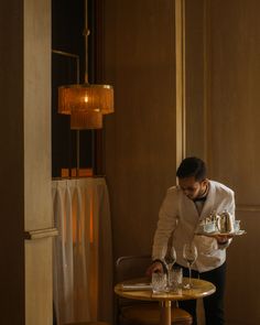 a man standing at a table holding a cake and wine glass in his hand while wearing a white shirt