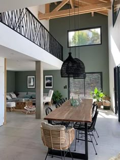 a dining room table and chairs in front of an open floor plan with high ceilings