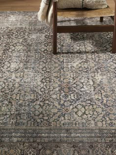 a large rug with an ornate design on the floor in front of a wooden chair