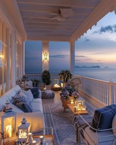 an outdoor living area with couches and candles on the balcony overlooking the ocean at dusk