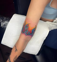 a woman's arm with a colorful tattoo on it, sitting in a chair