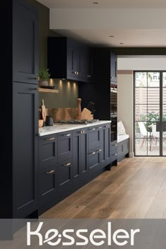 a kitchen with dark blue cabinets and white counter tops, wood flooring and glass doors leading to an outside patio