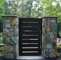 an open black gate in front of a stone wall