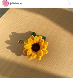 a yellow flower is sitting on top of a wooden table with a keychain attached to it