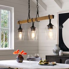 a dining room table with four lights hanging over it