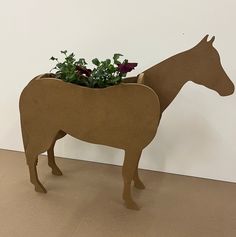 a planter shaped like a horse with flowers in it