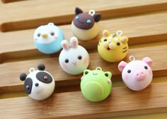 small plastic animal charms sitting on top of a wooden table next to each other in different colors