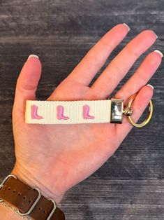 a hand with a wrist strap that has pink arrows on it and two gold rings