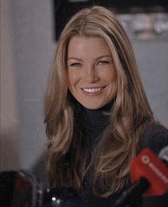 a woman with long hair is smiling and holding microphones in front of her face