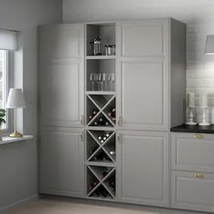 a kitchen with white cabinets and wine glasses on the bottom shelf in front of it