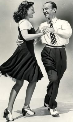 an old photo of two people dancing with one holding his arm around the other's waist