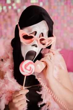 a person wearing a mask and holding a lollipop