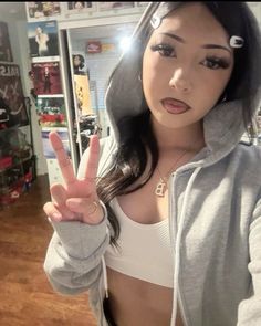 a young woman making the peace sign with her fingers and wearing a hoodie in a store