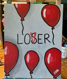 a painting with red balloons and the words lover written on it in black ink, sitting on a easel