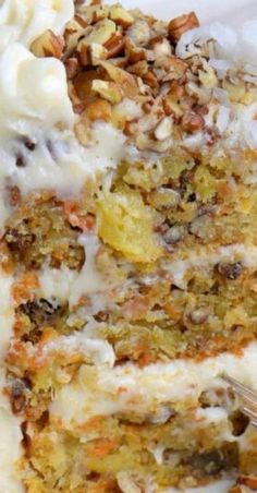 a piece of carrot cake with cream cheese frosting and chopped nuts on the top