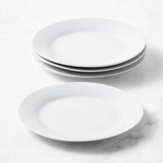 three white plates sitting on top of a marble counter next to each other in front of a wall