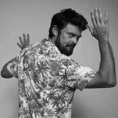 black and white photograph of man in hawaiian shirt holding his hands up to the side