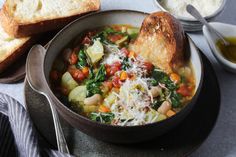 a bowl filled with soup next to two slices of bread on top of a table