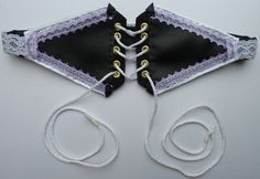 two pieces of black and white fabric with gold laces on them, tied together