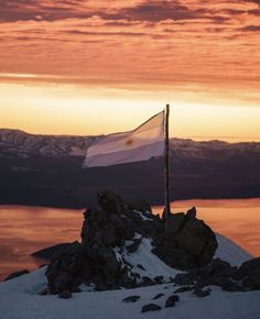 a flag on top of a mountain at sunset