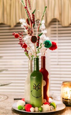 two bottles with flowers in them sitting on a table next to candles and candy canes