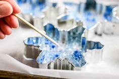 a person holding a paintbrush in front of some blue and white cake pans