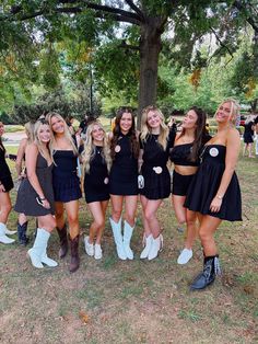 a group of young women standing next to each other on top of a grass covered field