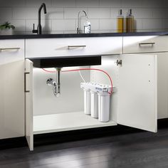 a kitchen with white cabinets and black counter tops, an open dishwasher is shown