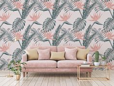 a pink couch sitting in front of a wallpaper with palm leaves on it's side