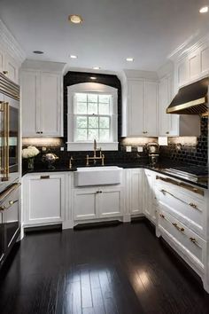 a large kitchen with white cabinets and black counter tops, along with dark wood flooring