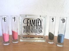 three glass vases sitting next to each other on top of a wooden table with the words family where life begins and love never ends