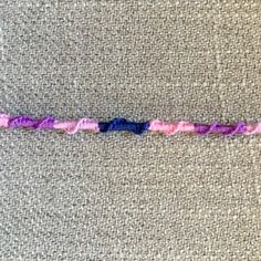 a close up of a piece of cloth with pink and blue thread on it's edge