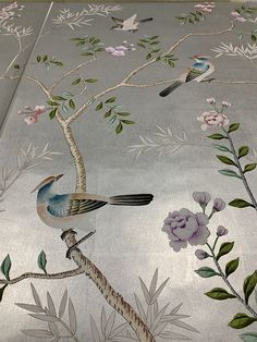 a bird sitting on top of a tree branch next to flowers and birds in the sky