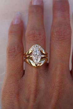 a woman's hand wearing a gold ring with two pear shaped diamonds on it