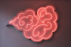 a neon sign that is on the side of a wall with clouds and hearts painted on it