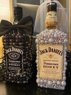 two bottles of jack daniels whiskey on a table next to a black bag with pearls