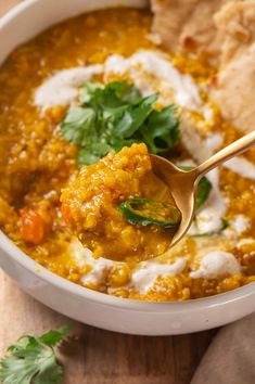 a white bowl filled with soup next to tortilla chips and cilantro