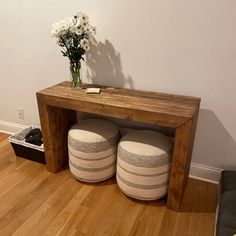 a wooden bench with two stools underneath it and flowers in vase on the table