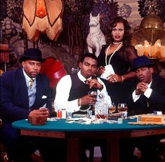 three men and a woman sitting at a table with drinks in front of the camera