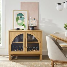 a wooden cabinet with wine glasses and bottles on it next to a dining room table