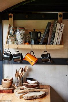 a wooden table topped with pots and pans next to a shelf filled with books